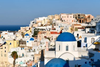 Yunanistan 'ın Santorini adasındaki Oia köyünün büyüleyici manzarası. Ege Denizi 'ndeki Caldera üzerinde geleneksel mavi kubbe kilisesi. Geleneksel mavi ve beyaz Cyclades mimarisi.