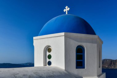 Yunanistan 'ın Santorini adasındaki Oia köyünün büyüleyici manzarası. Ege Denizi 'ndeki Caldera üzerinde geleneksel mavi kubbe kilisesi. Geleneksel mavi ve beyaz Cyclades mimarisi.