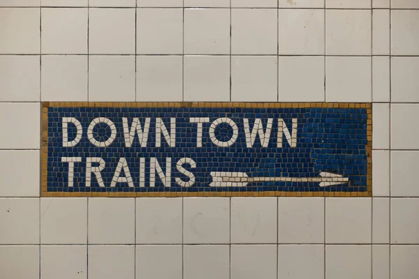 Tiled New York City subway train sign with arrow pointing direction.