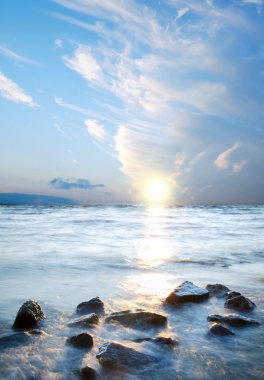 Deniz suyu günbatımı arka plan üzerinde taşlar