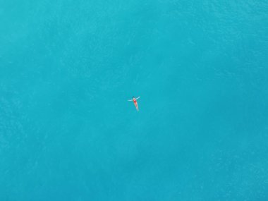 a young woman floats on the sea in red bikini