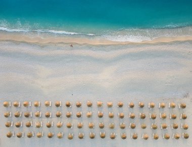 aerial view of sandy beach with sea waves and umbrellas on the sandy shore