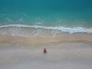 Aerial view of a young couple sitting on the beach at sunset