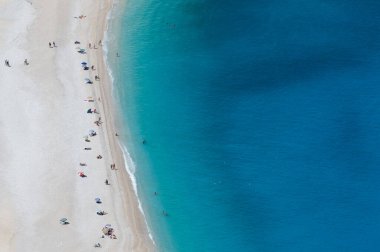 aerial view of a sandy beach with turquoise water and umbrellas