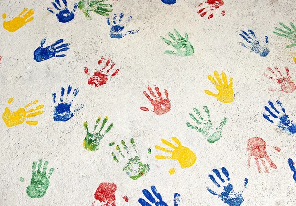 Mãos multicoloridas na parede branca — Fotografia de Stock