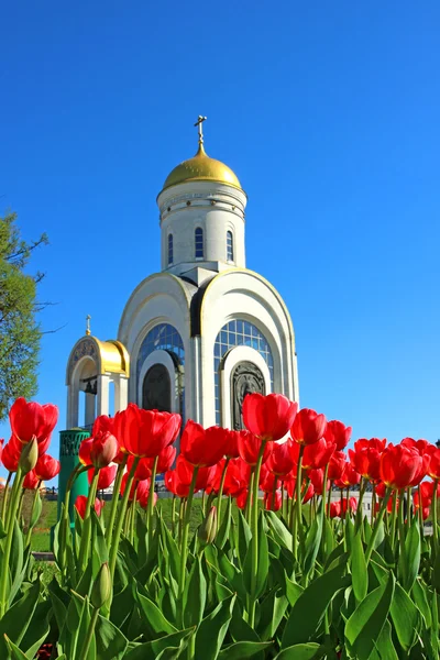 Tulipanes rojos frente a una iglesia cristiana —  Fotos de Stock