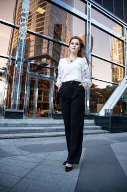 Sokaktaki genç iş kadını, arkasında cam ayna olan.