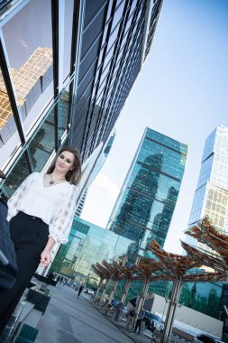 Modern gökdelenlerin şehrinde gülümseyen genç iş kadını