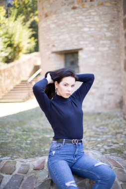 Eski taş binanın yanında kot pantolonlu, Avrupalı genç bir kız.