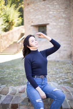 Eski taş binanın yanında kot pantolonlu, Avrupalı genç bir kız.