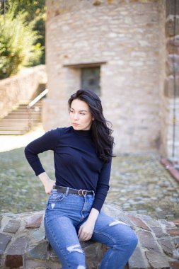 Eski taş binanın yanında kot pantolonlu, Avrupalı genç bir kız.