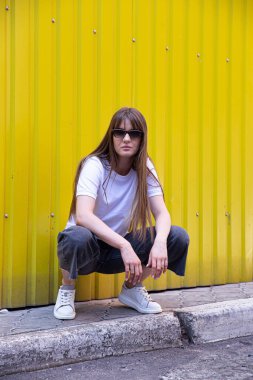 Oturan beyaz Avrupalı kadın koyu saçlı kısmen sarı arkaplan