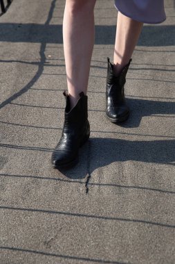 Asfaltta siyah çizmeli beyaz kadın bacakları