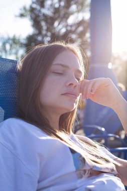 Dışarda gözleri kapalı, esmer, zayıf bir genç kadının portresi.