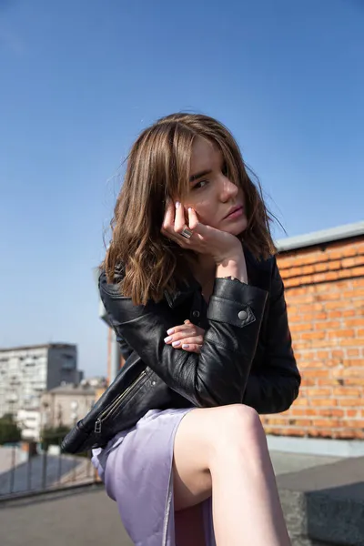 屋根の上に座って街の景色を背景に若いヨーロッパの女性 — ストック写真