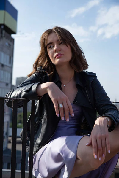 屋根の上に座って街の景色を背景に若いヨーロッパの女性 — ストック写真