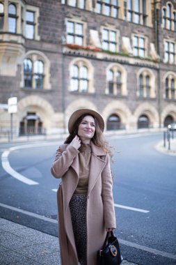 Kıvırcık saçlı, sonbahar ceketi ve şapkası olan güzel bir kadın.