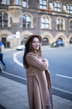 Kıvırcık saçlı, sonbahar ceketi ve şapkası olan güzel bir kadın.