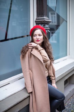 Kıvırcık saçlı, kırmızı bereli, pencereli güzel bir kadın.