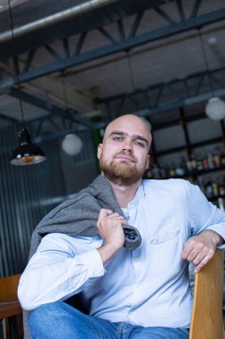 Beyaz Avrupalı kel, sakallı, gri gözlü, omuzunda ceketi olan bir adam.