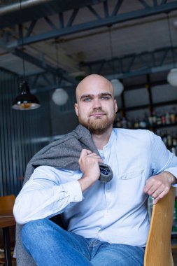 Beyaz Avrupalı kel, sakallı, gri gözlü, omuzunda ceketi olan bir adam.