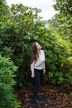 Arkasında ağaçlar olan beyaz kazaklı beyaz Avrupalı kadın.