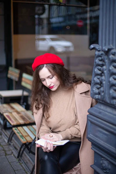 Красивая Женщина Вьющимися Волосами Красном Французском Берете Читает Книгу Улице — стоковое фото