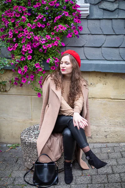 Красивая Женщина Вьющимися Волосами Красном Французском Берете Зданием Позади Цветами — стоковое фото