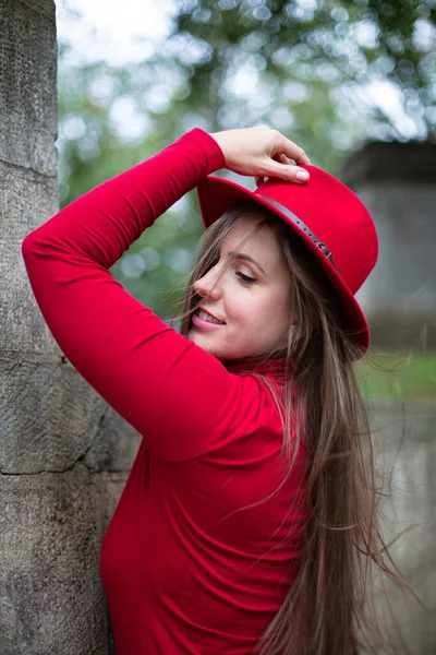 秋天公园石墙附近 一头乌黑的长发 头戴鲜红色 右手拿着帽子的白人妇女的画像 — 图库照片