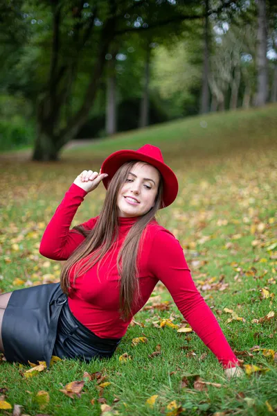 秋天公园的草地上坐着一头乌黑的长发 红红的 闭着眼睛的白女人 — 图库照片