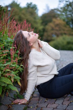 Parkta beyaz kazaklı beyaz kadın