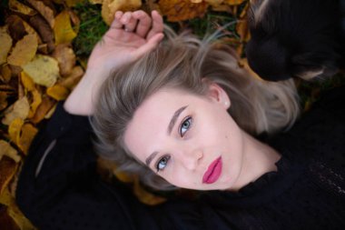 Sonbahar yeşilliklerinde siyah kazaklı beyaz Avrupalı kadın.