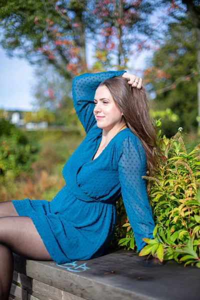 穿着浅蓝色衣服在秋天的公园里笑着的年轻的欧洲白人女人 — 图库照片