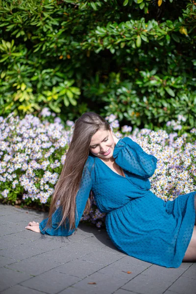 Siedząca Biała Młoda Europejka Pobliżu Kwiatów Jasnoniebieskim — Zdjęcie stockowe