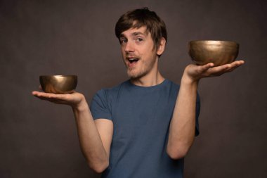 Genç yakışıklı, uzun boylu, zayıf, kahverengi saçlı, mutlu görünen gri arka planda mavi gömlekli bir adam.