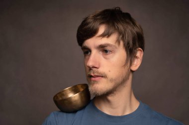 Genç yakışıklı, uzun boylu, zayıf, kahverengi saçlı, gri arka planda mavi gömlekli, dengeli bir adam.