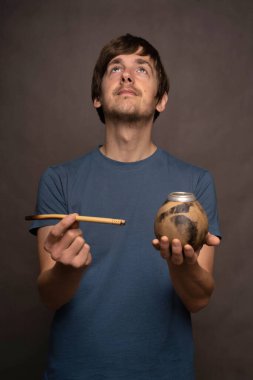 Kahverengi saçlı, uzun boylu, zayıf beyaz bir adam elinde kupa olan gri arka planda mavi gömlekli bir adam.