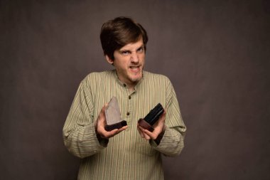 Genç yakışıklı, uzun boylu, zayıf, kahverengi saçlı, gri arka planda siyah beyaz kristaller tutan beyaz adam.