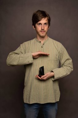 Genç yakışıklı, uzun boylu, zayıf, kahverengi saçlı, gri arka planda siyah kristal gömlekli, havada asılı duran beyaz adam.