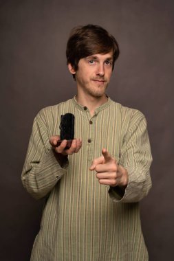 Genç yakışıklı, uzun boylu, zayıf, kahverengi saçlı, siyah kristalli, gri arka planda çizgili gömlekli, beyaz bir adam.