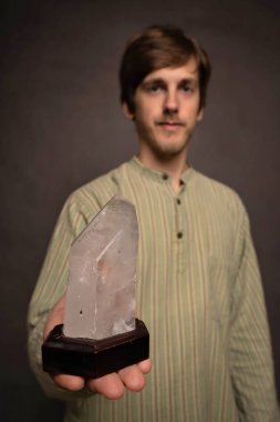 Genç yakışıklı, uzun boylu, zayıf, kahverengi saçlı, gri arka planda büyük kristal çizgili gömleği olan beyaz bir adam.