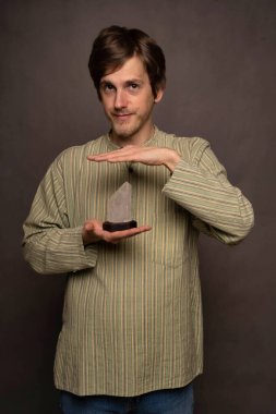 Yakışıklı, uzun boylu, zayıf, kahverengi saçlı, elleri çizgili gri arka planda kristal bir adam.