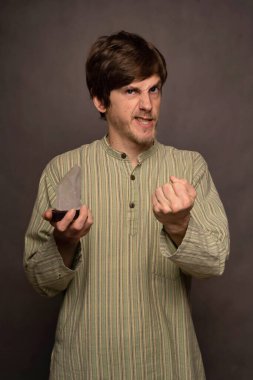 Genç yakışıklı, uzun boylu, zayıf, kahverengi saçlı, gri arka planda kristal gömlekli, beyaz bir adam.