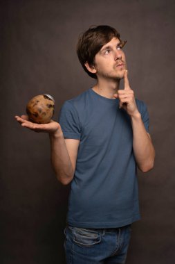 Genç yakışıklı, uzun boylu, zayıf, kahverengi saçlı, mat bardağı elinde tutan gri gömlekli gri arka planlı beyaz adam.