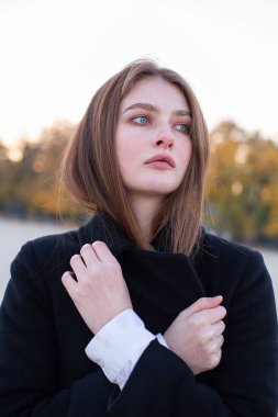 Sonbaharda kumsalda koyu renk ceketli, uzun düz saçlı beyaz Avrupalı bir kadının portresi.