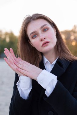 Sonbaharda kumsalda koyu renk ceketli, uzun düz saçlı beyaz Avrupalı kadının portresi.