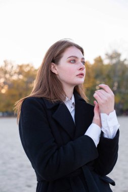 Sonbaharda kumsalda koyu renk ceketli, uzun düz saçlı beyaz Avrupalı kadının portresi.