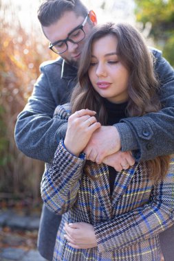 Sazlıkların yanında beyaz adam ve kadını kucaklayan portre.