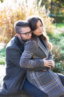 Arkasında sazlıklar olan beyaz erkek ve kadını kucaklayan romantik bir adam.