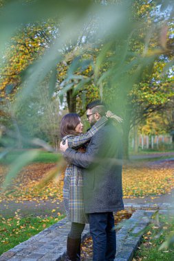 Sonbahar parkında siyah saçlı beyaz Avrupalı erkek ve kadını kucaklamak